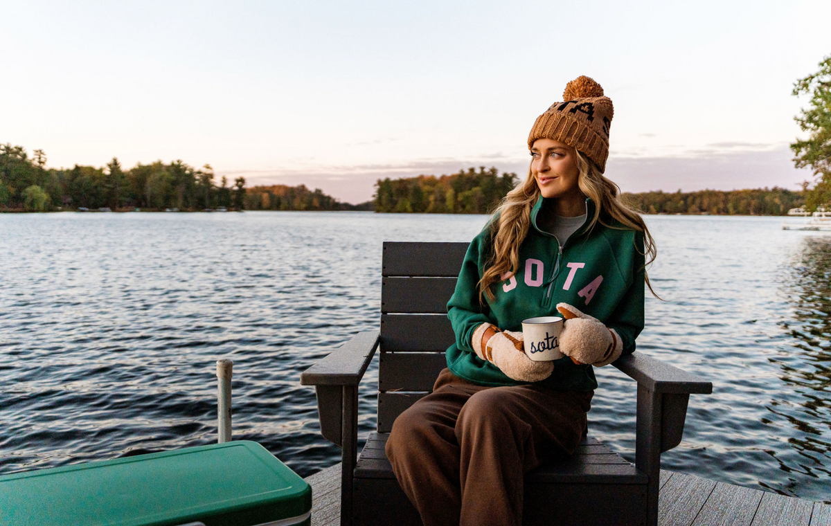 A woman in the Lila half-zip on a dock at the lake