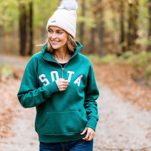 Person wearing a green sweatshirt with 'SOTA' text in a forest setting