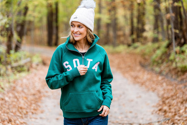 Person wearing a green sweatshirt with 'SOTA' text in a forest setting
