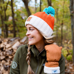 Person wearing a colorful knit sota hat and green jacket in a forest setting
