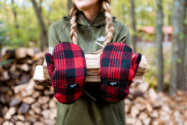 woman carrying firewood with cozy minnesota mittens.