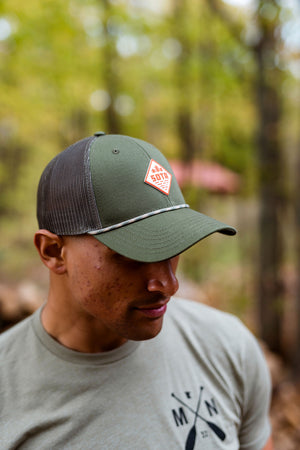 Man wearing a green cap with a Minnesota logo in a forest setting