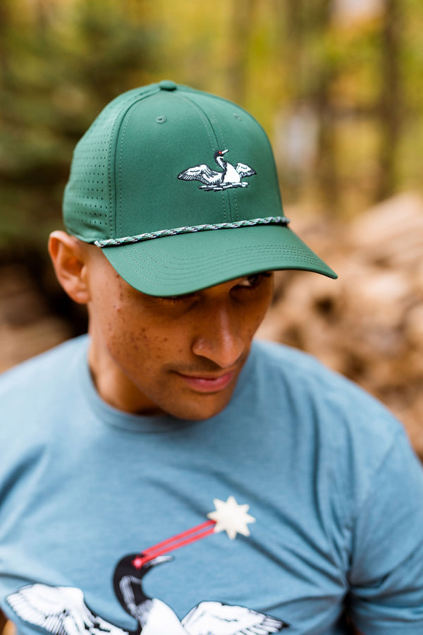 Man wearing a green cap with a laser loon logo in a forest setting