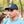 Man wearing a blue t-shirt with a laser loon graphic design and a minnesota-centric black cap with hockey sticks  in a forest setting