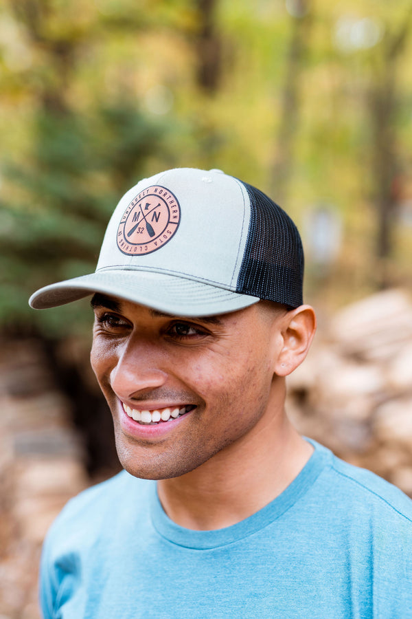 Person wearing a trucker cap with a Minnesota logo in a forest setting
