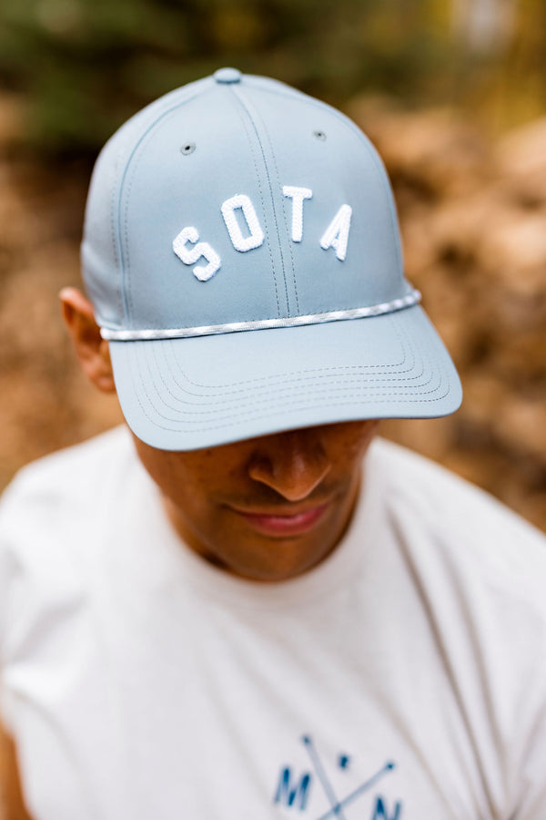 Person wearing a light blue cap with 'SOTA' text in a forest setting