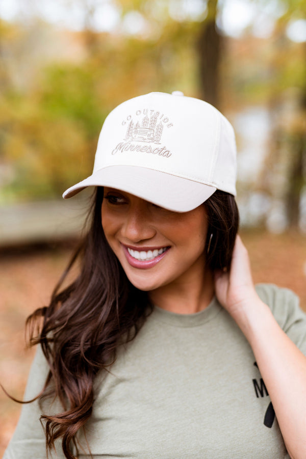 Woman wearing a beige cap with a minnesota logo outdoors