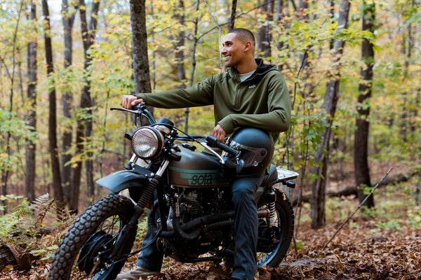 Man sitting on a motorcycle in a forest during autumn