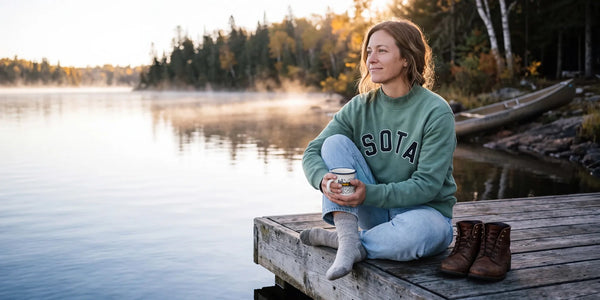 A woman in the basil Fernwood mock neck on a dock at sunrise